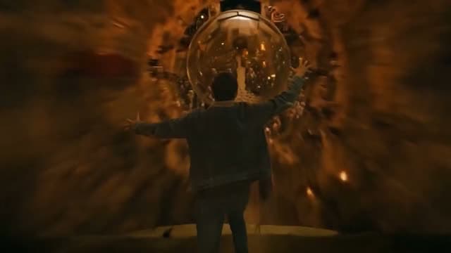 Clip of a lone figure facing a glowing orb in a dark tunnel with warm amber light